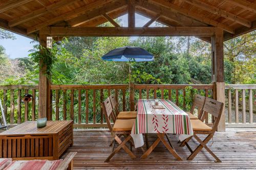 une table et des chaises sur une terrasse avec un parasol dans l'établissement Les chats perchés 400m plage G, à Labenne