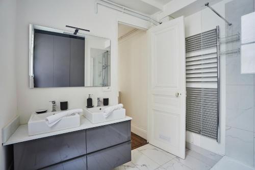 a white bathroom with two sinks and a mirror at Apartment beaubourg by Studio prestige in Paris