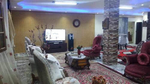 uma sala de estar com sofás e uma televisão e um quarto com em Obour apartment, first district, Tabbah view em ‘Ezbet el-Insha