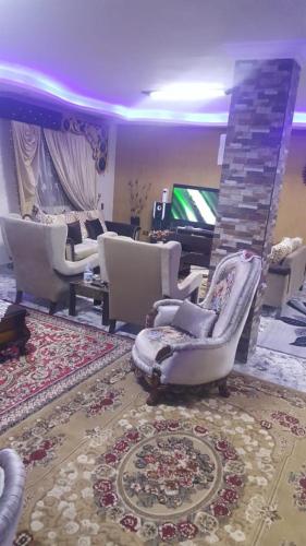 - un salon avec des chaises blanches et un jeu vidéo dans l'établissement Obour apartment, first district, Tabbah view, à ‘Ezbet el-Insha