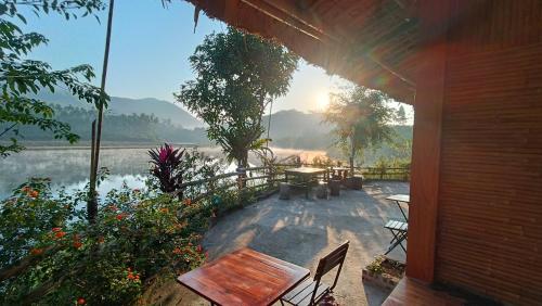 una casa con mesa, sillas y un lago en Giang Tien Homestay-VuLinh Farmstay ThacBa en Yên Bình