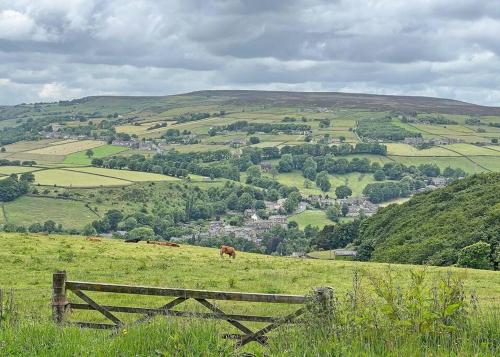 Blick auf ein grünes Feld mit einem Holzzaun in der Unterkunft Apple Cottage: 19th Century Charm in Calder Valley in Luddenden Foot