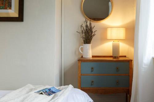 ein Schlafzimmer mit einer Kommode mit einer Lampe und einem Spiegel in der Unterkunft Apple Cottage: 19th Century Charm in Calder Valley in Luddenden Foot