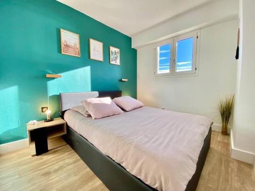 une chambre avec un lit avec un mur bleu dans l'établissement Cannes Les Plages By SCLS Locations, à Cannes