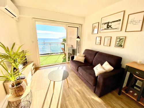 un salon avec un canapé et une grande fenêtre dans l'établissement Cannes Les Plages By SCLS Locations, à Cannes