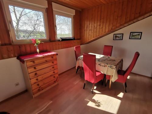 a dining room with a table and red chairs at Ferienwohnung am Sonnenberg in Hammelbach