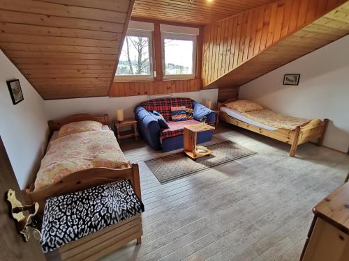 Schlafzimmer im Dachgeschoss mit 2 Betten und einem Sofa in der Unterkunft Ferienwohnung am Sonnenberg in Hammelbach
