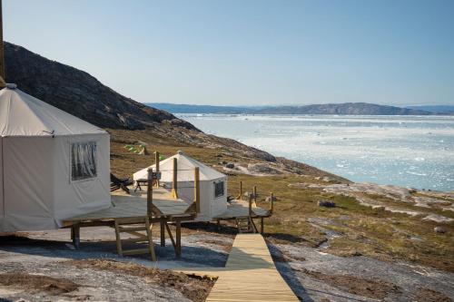 eine Gruppe von Zelten auf einem Hügel neben dem Wasser in der Unterkunft Glacier Lodge Eqi in Ilulissat