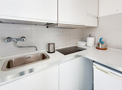 uma cozinha com armários brancos e um lavatório em Attico a Marina Centro em Rimini