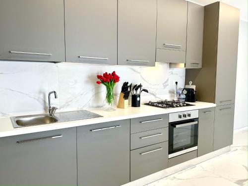 a kitchen with white cabinets and a vase of red flowers at Donnino Apartments in Fidenza