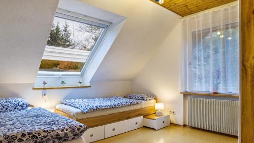 two beds in a room with two windows at Ferienwohnungen Seeblick in Unterkirnach