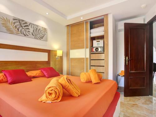 een slaapkamer met een oranje bed met handdoeken erop bij ZEN HOLIDAYS, Heated Pool, Cond Air, Terrace in San Miguel de Abona