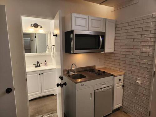 a kitchen with white cabinets and a sink and a microwave at A la Veta Guest Studio in Albuquerque