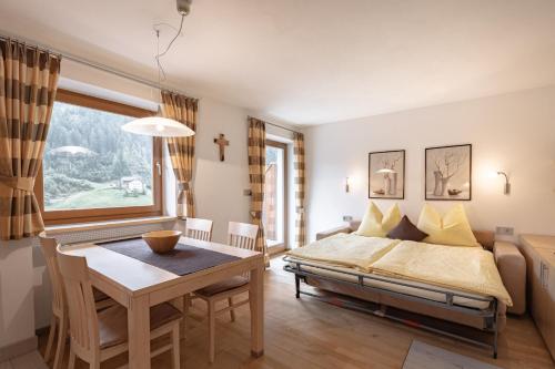 a bedroom with a bed and a table and a window at Apartments Soval in Santa Cristina Gherdëina