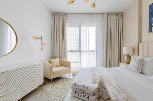 a white bedroom with a bed and a chair at Nasma Luxury Stays - Fabulous Apartment With Balcony Near MJL's Souk in Dubai
