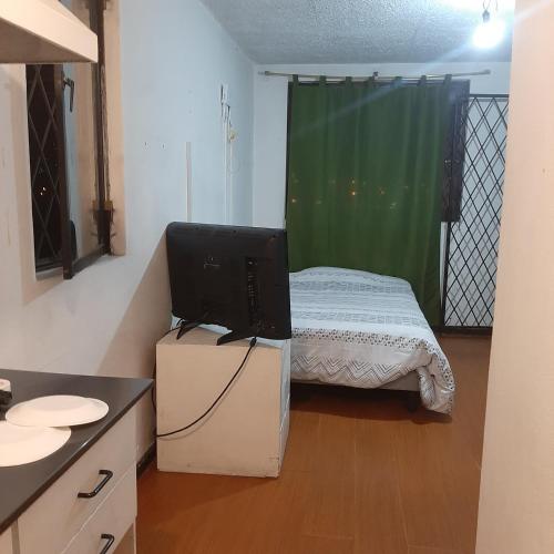 ein kleines Schlafzimmer mit einem Bett und einem TV auf einer Kommode in der Unterkunft Maya Suite in Cuenca