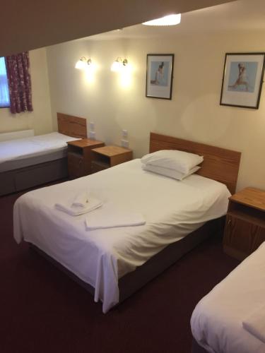 a hotel room with two beds and two tables at Oak house hotel in Wellingborough