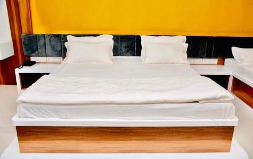 Hotel 7 Seas في Mundra: سرير كبير عليه أغطية ووسائد بيضاء