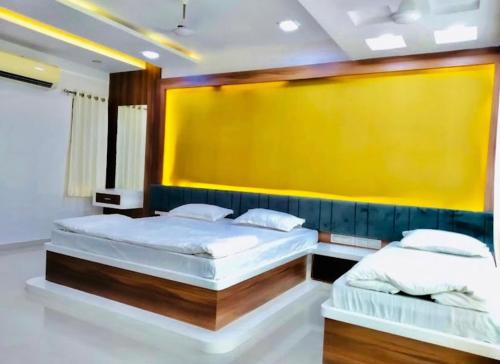two beds in a room with a yellow wall at Hotel 7 Seas in Mundra