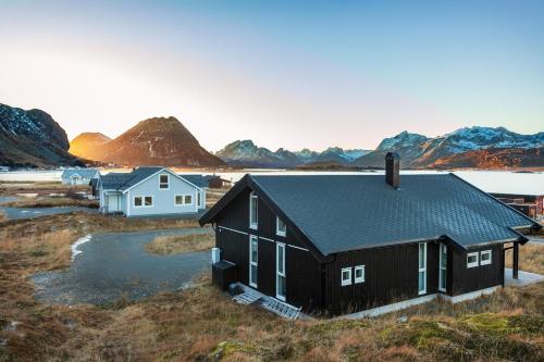 a black house with mountains in the background at Vaeranes- Ny hytte med flott utsikt in Ramberg