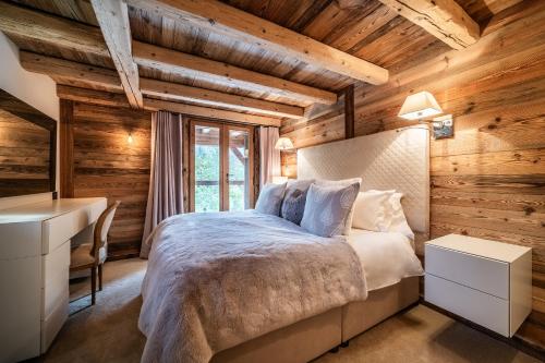 1 dormitorio en una cabaña de madera con cama y escritorio en Chalet La Ferme du Gron Les Carroz - BY EMERALD STAY, en Les Carroz d'Araches