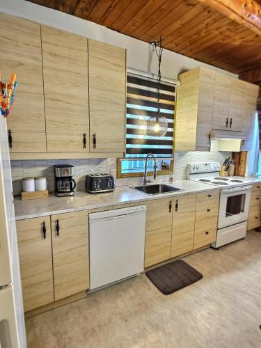a kitchen with wooden cabinets and a sink at Nelson Log Cabin in Rivière-Rouge in Rivière-Rouge