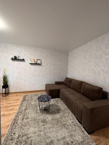 a living room with a brown couch and a rug at Jaukus butukas in Kėdainiai