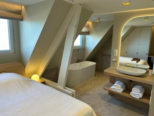 a bathroom with a bed and a tub and a sink at Face à la mer in Gravelines