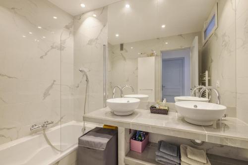 une salle de bain avec deux lavabos, une baignoire et un miroir dans l'établissement Appartement de standing Cannes, à Cannes