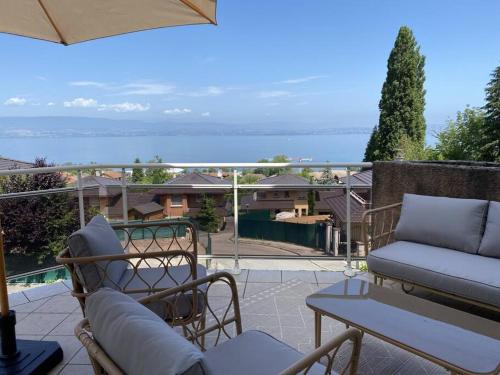 a patio with a couch and chairs on a balcony at Magnifique Appart rénové Evian vue Lac 8 pers in Évian-les-Bains