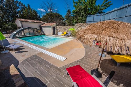 una piscina con sombrilla y sillas de paja en Gîte avec jacuzzi privatif dans un mas provençal, en Les Fumades-Les Bains