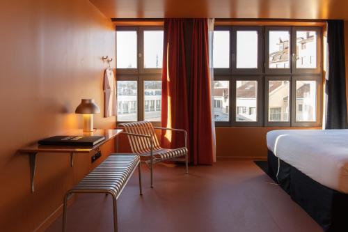 Pokój hotelowy z łóżkiem, biurkiem i oknem w obiekcie Pilo Lyon w mieście Lyon