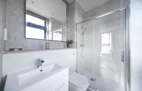 a white bathroom with a shower and a sink at Fabulous & New - Private Balcony - Station Nearby in Orpington