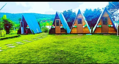 a group of tiny houses in a grass field at LAKE FRONT CAMPING AND COTAGE in Lonavala