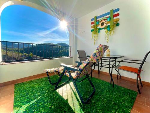 a room with a balcony with a chair and a table at Apartamentos Axarquia , Frigiliana, terraza privada con vistas a la montaña rio y al mar in Frigiliana