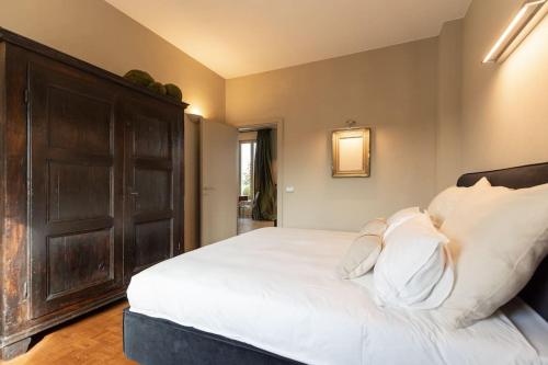 Schlafzimmer mit einem großen weißen Bett und einer Holztür in der Unterkunft L'Attico vicinissimo all'Ospedale di Cuneo con grande terrazzo in Cuneo