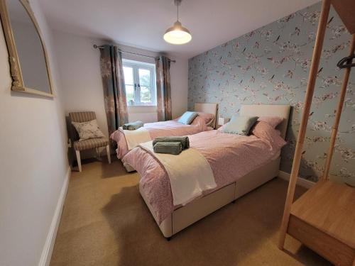 a bedroom with two beds and a chair at Beck View in Norwich