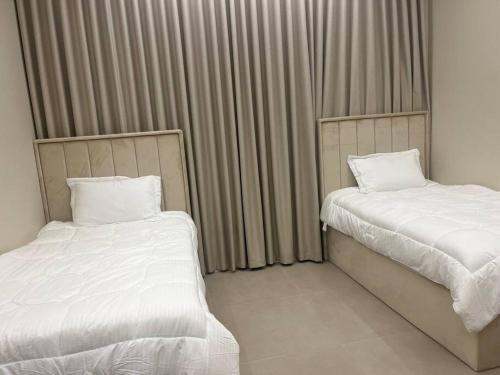 two beds in a hotel room with curtains at Moon light in Sharīyah
