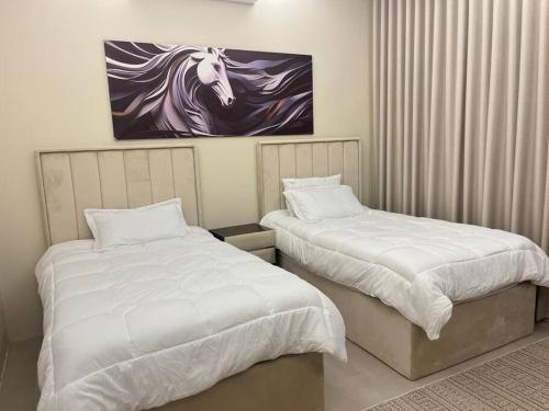 ein Schlafzimmer mit 2 Betten und ein Gemälde eines Pferdes in der Unterkunft Moon light in Sharīyah