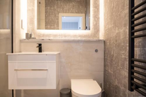 uma casa de banho com um lavatório branco e um espelho. em NEW & Spacious - Private Balcony - Station Nearby em Farnborough