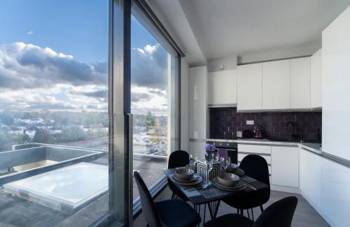 a kitchen with a table and chairs and a large window at Palm Tree House Apartments in Farnborough