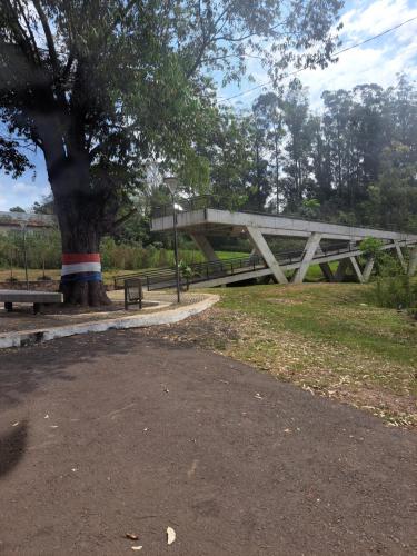 a park with two benches and a tree with a bridge at Casa colonial a metros del arroyo Piribebuy in Piribebuy