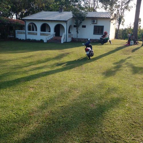 a person riding a scooter in front of a house at Casa colonial a metros del arroyo Piribebuy in Piribebuy