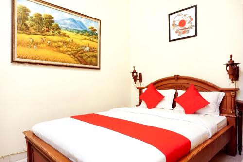 a bedroom with a bed with a painting on the wall at The Homey Rooms and Tours in Yogyakarta