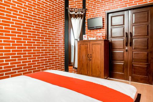 a bedroom with a bed and a brick wall at The Homey Rooms and Tours in Yogyakarta