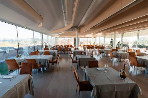 アルバにあるHotel Ristorante I Castelliのテーブルと椅子、窓のあるレストラン