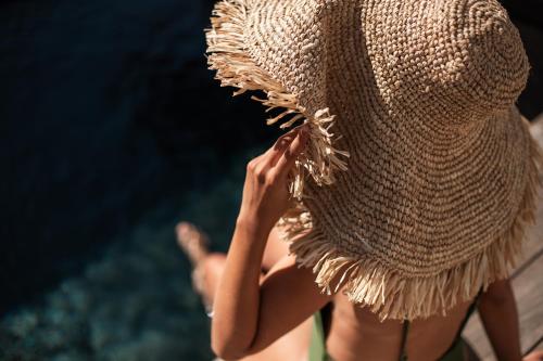 a woman in a straw dress standing on a dock at Hôtel Cala di Greco in Bonifacio