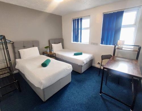 a room with two beds and a table and two windows at Royal Chambers Liverpool in Liverpool