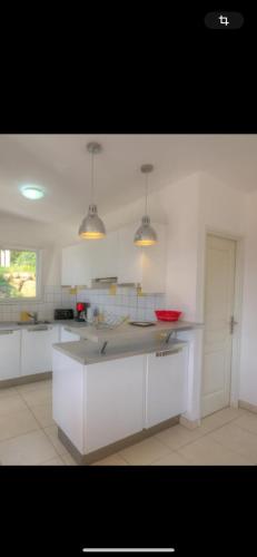 une cuisine avec des armoires blanches et un comptoir dans l'établissement Villa les MYRTES, à Olmeto