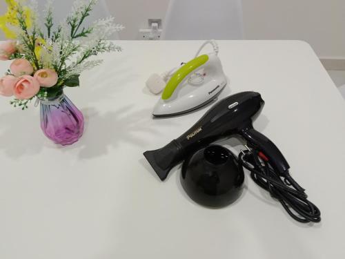 a white table with a vase of flowers and a phone at Habibi HoMe KLCC in Kuala Lumpur